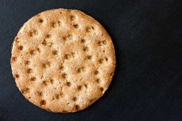 Single rye crispbread from above isolated on black.
