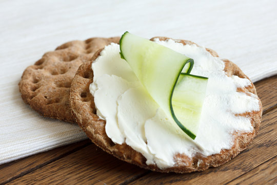 Two round rye crispbreads on wood with white napkin. Top one spr