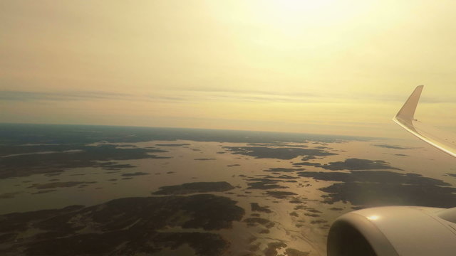 Airplane flying at low altitude over sea and islands at sunset
