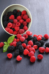 raspberries and blackberries in a bowl black background