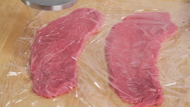 Flattening a veal escalope wrapped in cling film