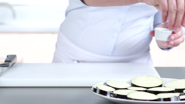 Aubergine slices being sprinkled with salt