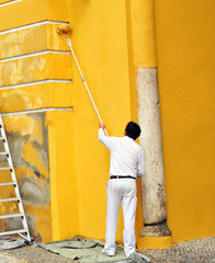 Man painting the facade of a monument with a roller