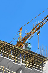 Crane and building construction site against blue sky
