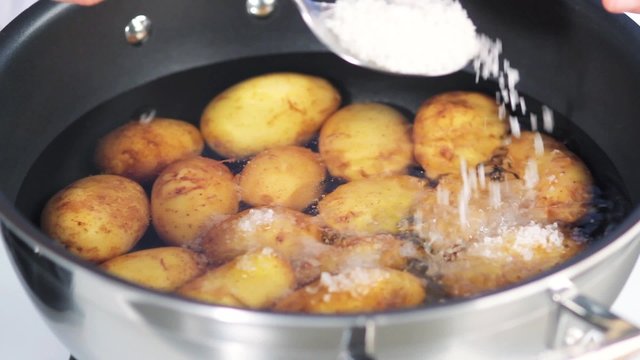 Potatoes in water being sprinkled with sea salt
