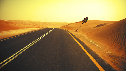 Winding black asphalt road through the sand dunes of Liwa oasis, United Arab Emirates