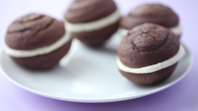 A hand taking a chocolate whoopie pie from a plate