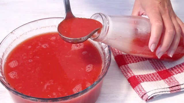 Home-made tomato juice being spooned into a bottle