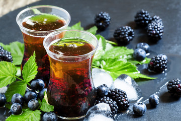 Cold black tea with berries and ice, selective focus