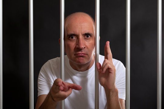 Man in jail gesturing guns with his hands