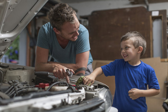 Son Helping Father In Home Garage Working On Car