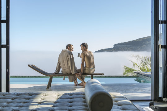Two young men drinking coffee at the poolside