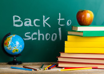 Back to school supplies. Books and blackboard on wooden backgrou
