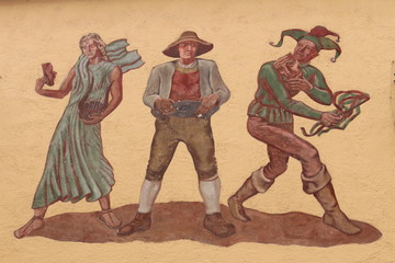 Fototapeta na wymiar Historical murals with three human figures on a wall on Wallpachgasse street in Hall in Tirol, Austria. 