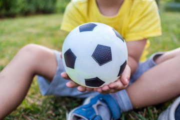 little boy is holding a ball with his both hands