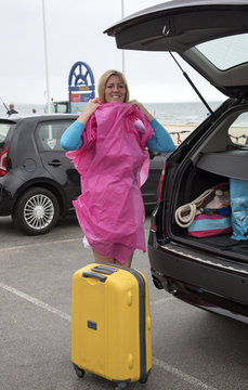 Female holidaymaker at a wet seaside resort unpacking her car. UK