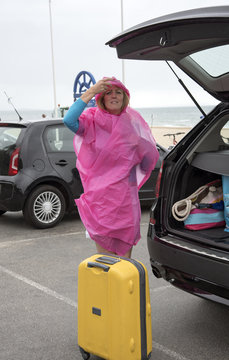 Female holidaymaker at a wet seaside resort unpacking her car. UK