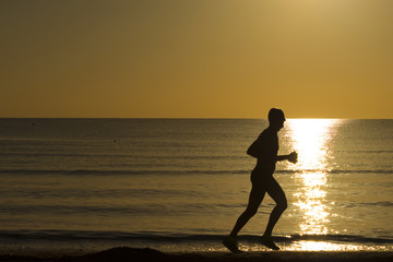 man running on the beach at dawn