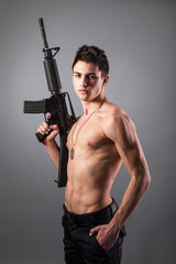 Handsome bare-chested soldier is holding a rifle