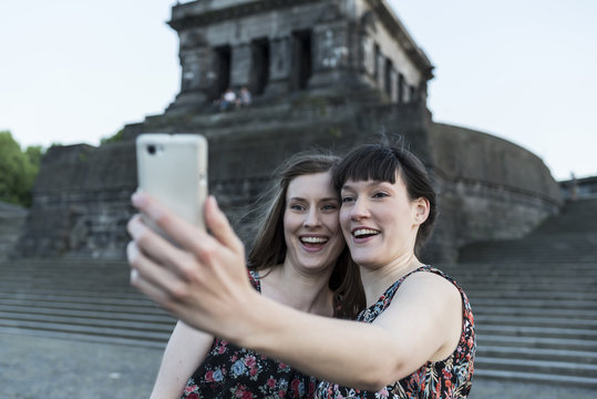 Germany, Koblenz, Deutsches Eck, tourists taking selfie at Emperor-Wilhelm monument