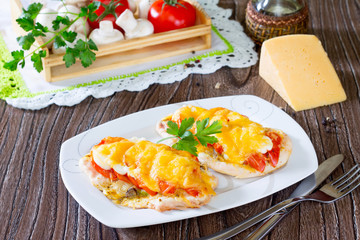 Chicken chops, fillets baked with mushrooms and cheese on a wood