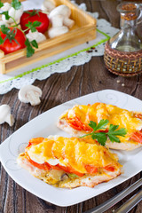 Chicken chops, fillets baked with mushrooms and cheese on a wood