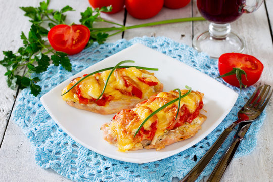 Chicken chops, fillet, baked with tomatoes and cheese on wooden