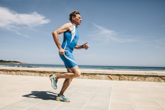 Spain, Mallorca, Sa Coma, triathlete running along beach promenade