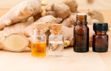 Bottles of ginger oil and ginger on wooden background with selec