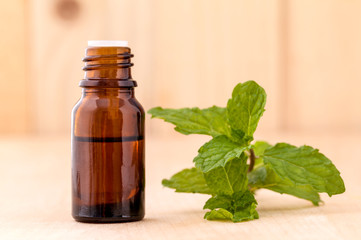 Bottle of mint essential oil on wooden background with selective