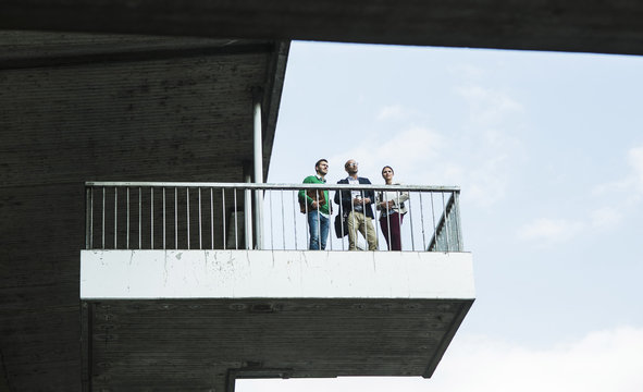 Three businesspeople standing on platform under a bridge