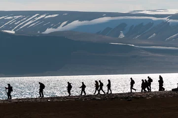  Gesilhouetteerde groep wandelaars in Barentsoya, Svalbard, Noorwegen. © Don Landwehrle