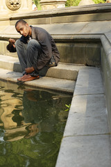 Man seated on stonework gives thumbs down.