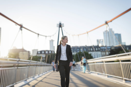 Businesswoman walking on a bridge at twilight