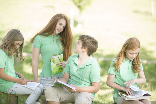 Group of pupils with exercise books and leaves in a park