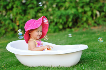 little girl bathes in a bath with soap bubbles