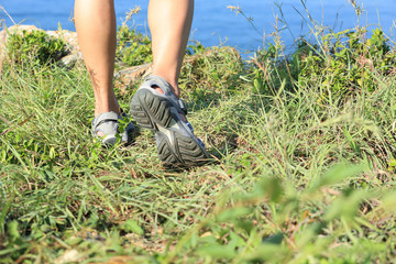 woman hiker legs hiking on seaside mountain grass