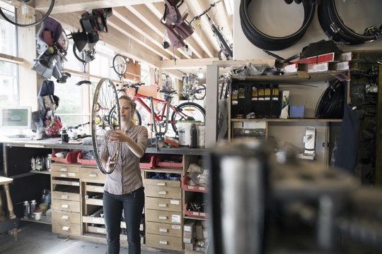 Young woman in a repair shop holding bicycle wheel