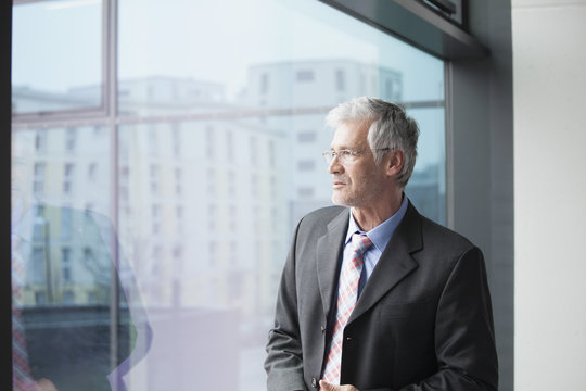 Businessman standing at window looking at distance