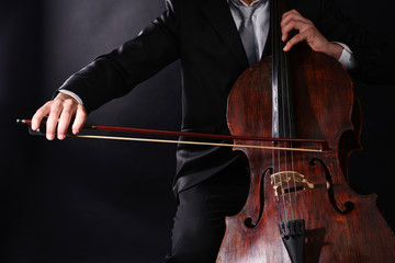 Man playing on cello on dark background