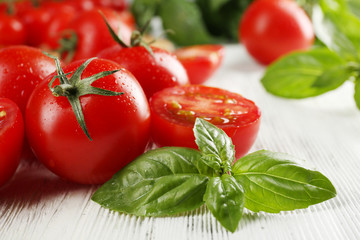 Cherry tomatoes with basil on wooden table close up