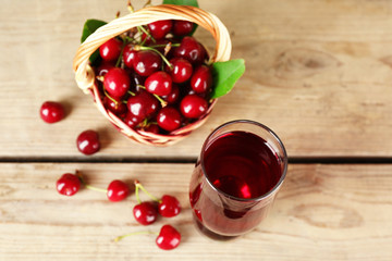 Glass of fresh juice with cherries on wooden table close up