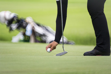 Female golfer marks her ball position on a green