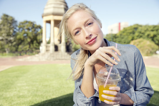 Young woman in park with soft drink