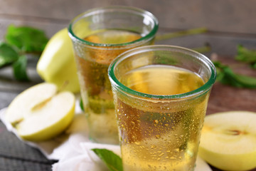 Wet glasses of apple juice on wooden table, closeup