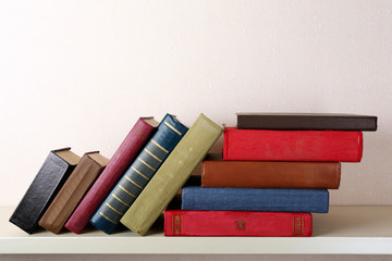 Old books on shelf, close-up, on light wall background