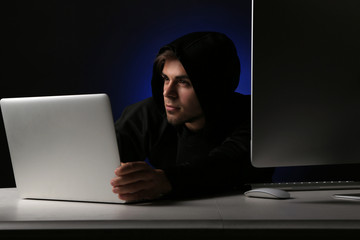 Hacker with computer and laptop on dark background