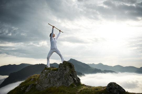 Austria, Kranzhorn, Mid adult woman exercising stick fighting on mountain top