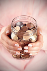 Woman holding money jar with coins close up