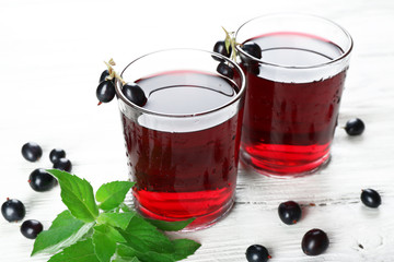 Glasses of fresh blackcurrant juice wooden table background